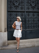 a lady wears a striped tank top with A-line white shorts